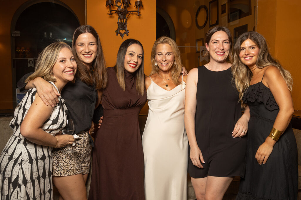 seis mujeres posan para una fotografía social, están vestidas de fiesta. fotografía de evento coporativo en Barcelona