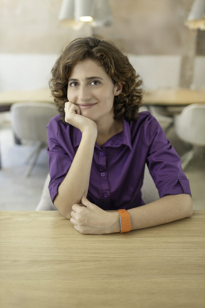 Retrato profesional de mujer joven apoyada en mesa en oficina moderna en Barcelona – fotografía corporativa natural por La Fotógrafa